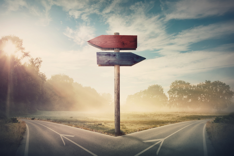 Surreal landscape with a split road and signpost arrows showing two different courses, left and right direction to choose. Road